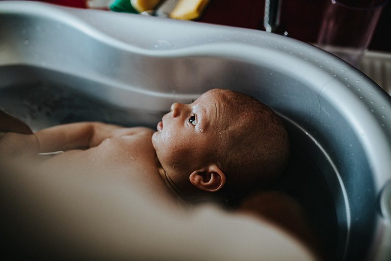 Bébé dans son bain, regard émerveillé — séance naissance ANtO photographe