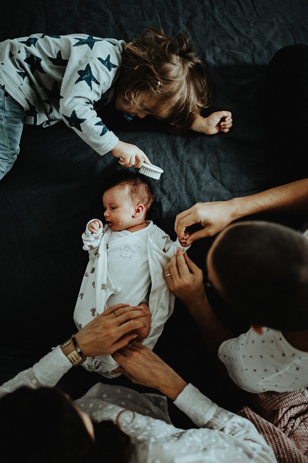 Grande sœur et parents autour du nouveau-né, moment de complicité familiale — ANtO photographe