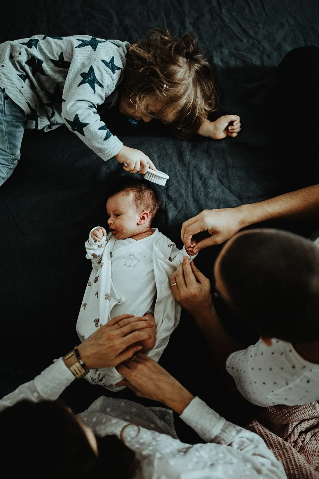 Grande sœur et parents autour du nouveau-né, moment de complicité familiale