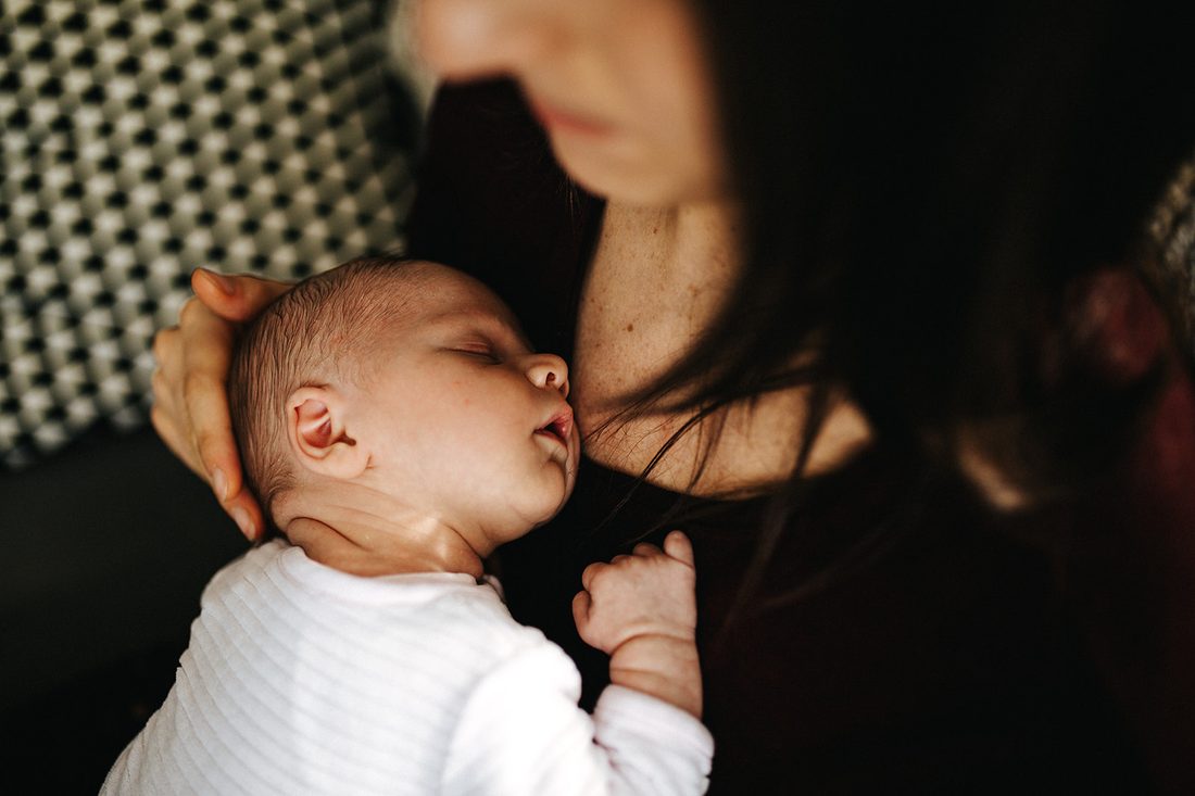 Mère berçant son nouveau-né endormi, lumière douce — séance naissance ANtO photographe