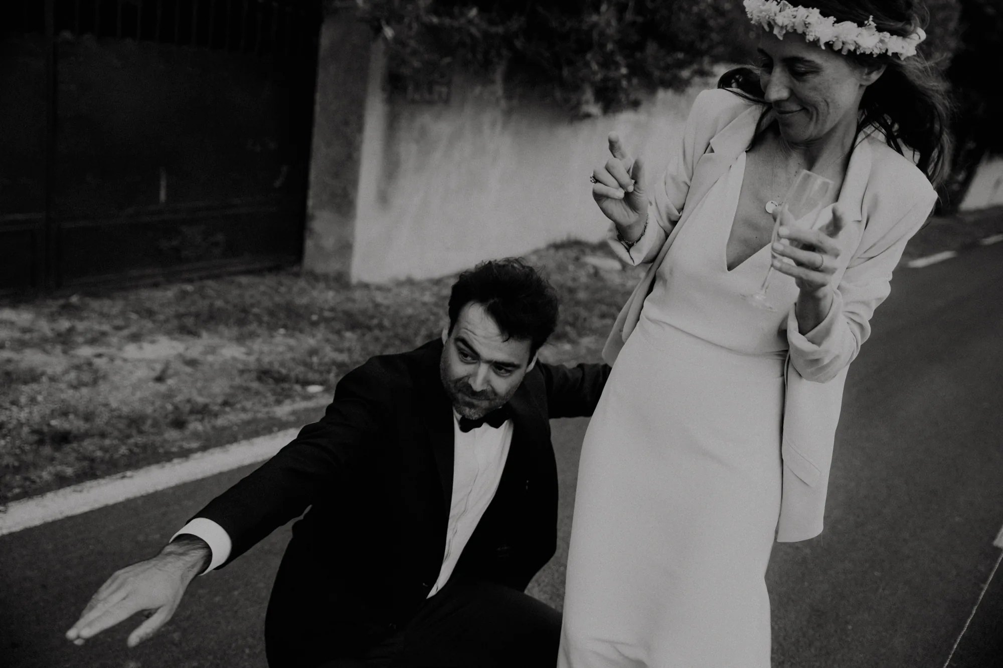 Les mariés rient dans la rue, elle en couronne de fleurs, coupe de champagne à la main — mariage Thiers Clermont-Ferrand, ANtO photographe